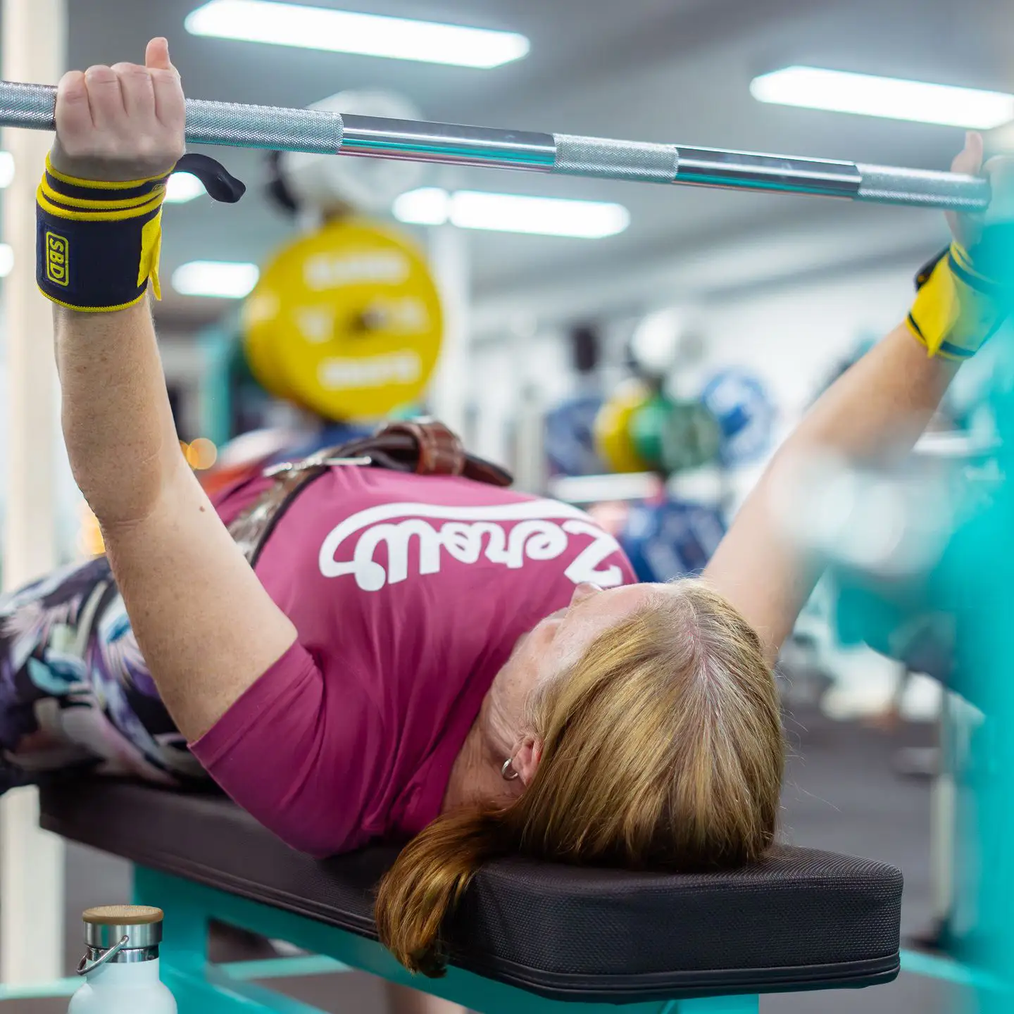 Female powerlifter pressing a heavy bench press in a ZeroW shirt